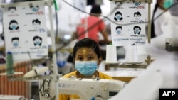 This photo taken on May 8, 2020 shows a worker wearing a face mask sewing disposable surgical gowns for health workers as protection from the COVID-19 coronavirus at a garment factory in Yangon. - The factory which has switched from making clothes for exp