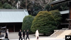 Japanese Prime Minister Shinzo Abe follows a Shinto priest to pay respect for the war dead at Yasukuni Shrine in Tokyo, Dec. 26, 2013. 