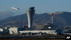 FILE - A plane takes off behind the air traffic control tower at San Francisco International Airport, in San Francisco, California, Nov. 24, 2020.