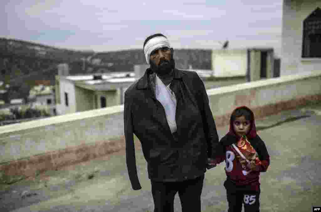 An injured Syrian man who just arrived on the Syrian side of the Bab al-Hawa border crossing between Syria and Turkey waits with his child outside a hospital.