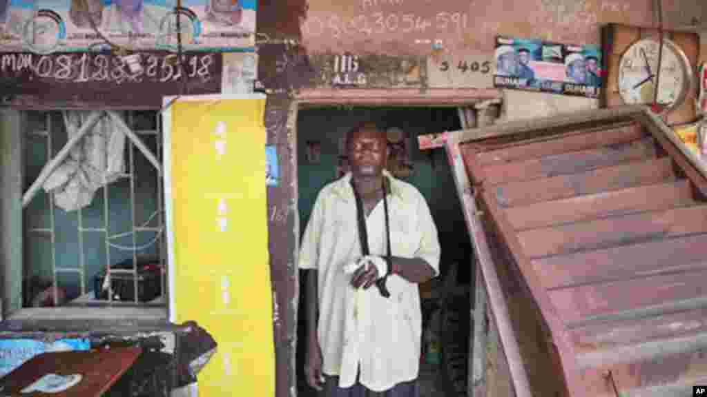 Yushau Ibrahim, stands outside his shop with an injured arm after security force raided and stole nearly $10,000 at Katangua market in Lagos.