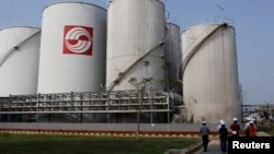 FILE - Officials walk by palm oil storage tanks at Indonesia's Sinar Mas Agro Resources refinery May 3, 2012