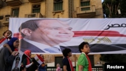 Egyptians walk by a poster for former Egyptian army chief Abdel Fattah al-Sisi in Tahrir square as they arrive to celebrate his victory in the presidential vote in Cairo, June 3, 2014.