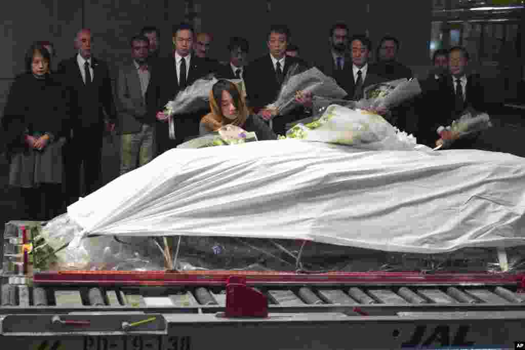 Family members and officials lay flowers at the coffin of slain Japanese doctor Tetsu Nakamura during a ceremony after transporting his body to his homeland, at Narita International Airport in Narita, near Tokyo.
