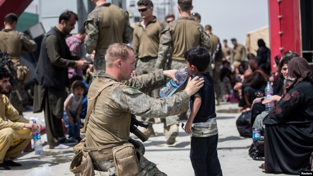 阿富汗首都喀布尔哈米德·卡尔扎伊国际机场。一名美国海军陆战队成员正在给一名孩子喝水。(photo:VOA)