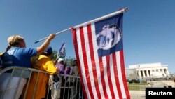 Seorang peserta pawai melmegang bendera Amerika bergambarkan Presiden Obama dalam peringatan 50 Tahun Pawai Washington di Monumen Lincoln, Washington (24/8). Presiden Obama akan menyampaikan pidato utama dalam puncak peringatan peristiwa bersejarah perjuangan hak sipil di monumen ini, Rabu (28/8).