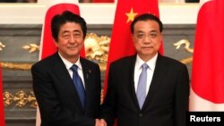 日本首相安倍晋三在东京与到访的中国总理李克强握手。（2018年5月9日）