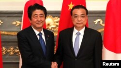 日本首相安倍晋三在东京与到访的中国总理李克强握手。（2018年5月9日）