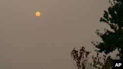 The sun appears orange through wildfire smoke, Sept. 16, 2020, in Olympia, Wash. The smoke from dozens of wildfires that have been raging across the western United States has now drifted thousands of miles across North America.