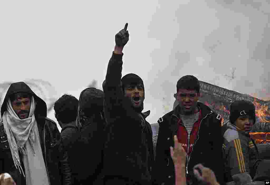 An Afghan man shouts anti-U.S slogans near a pile of tires set on fire by the protesters outside the U.S. military base in Bagram, February 21, 2012. (REUTERS)