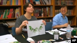 Undergraduate student Moe Lewis, left, shows her watercolor painting of peony leaves at a traditional Chinese painting class at the Confucius Institute at George Mason University in Fairfax, Va., on May 2, 2018. 