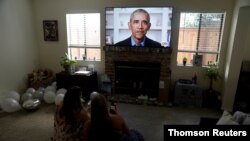 A graduating student in San Diego, Calif., and her sister watch former President Barack Obama deliver a virtual commencement address to millions of high school seniors who will miss graduation ceremonies due to the coronavirus outbreak, May 16, 2020.