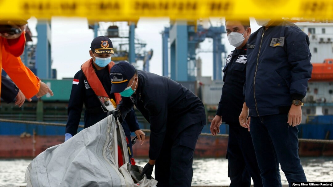 Anggota penyelamat membawa serpihan pesawat Sriwijaya Air penerbangan SJ182 yang jatuh ke laut, di pelabuhan Terminal Kontainer Internasional Jakarta, 10 Januari 2021. (Foto: REUTERS/Ajeng Dinar Ulfiana)