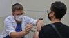 FILE - An Israeli health worker administers a third dose of the Pfizer-BioNtech COVID-19 vaccine to a patient, at the Maccabi Health Service in Jerusalem on August 20, 2021.