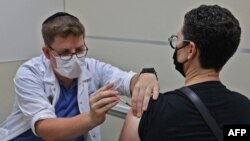 FILE - An Israeli health worker administers a third dose of the Pfizer-BioNtech COVID-19 vaccine to a patient, at the Maccabi Health Service in Jerusalem on August 20, 2021.