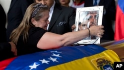 Liz Alban, hermana del ex concejal Fernando Alban, coloca un retrato de su pariente junto al de Jesucristo sobre su ataúd durante una ceremonia solemne en el Parlamento venezolano, el 9 de octubre de 2018, en Caracas.