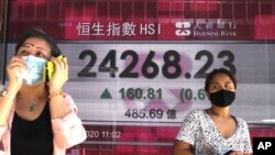 People walk past a bank's electronic board showing the Hong Kong share index at Hong Kong Stock Exchange, Nov. 2, 2020. 