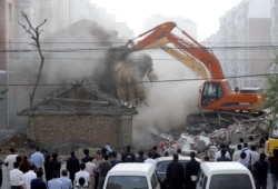 FILE - Chinese police and officials stand by as illegally-built houses are demolished in Changchun, northeast China's Jilin province, July 5, 2008.