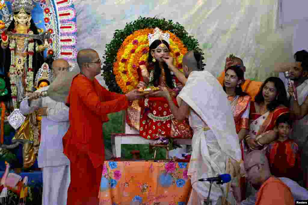 Dua pendeta Hindu mempersembahkan manisan kepada seorang gadis muda berpakaian Dewi &quot;Kumari&quot; selama festival Durga Puja, di sebuah kuil di Dhaka, Bangladesh. (Reuters)&nbsp;