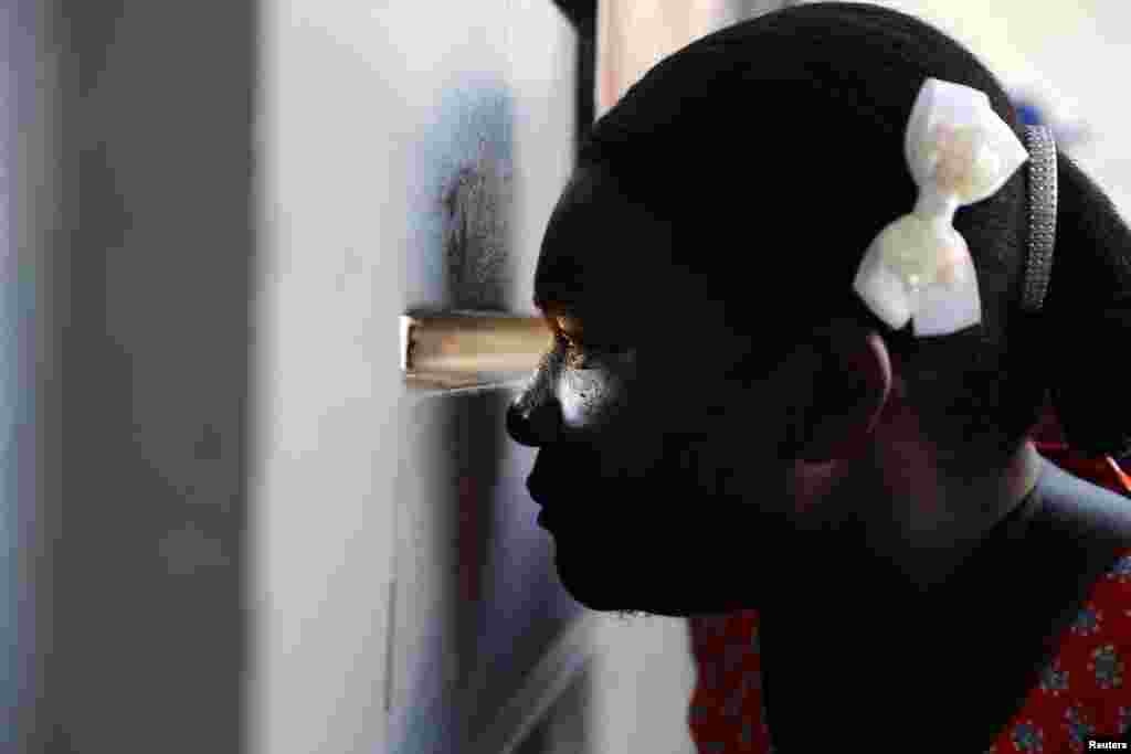 A Haitian woman looks through an opening of a gate of a migration clearance center where her husband had been taken, in Santo Domingo, Dominican Republic, Oct. 9, 2024. The Dominican Republic said it would deport up to 10,000 migrants per week who were in the country illegally.