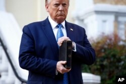 President Donald Trump holds a Bible as he visits outside St. John's Church across Lafayette Park from the White House, June 1, 2020, in Washington. Part of the church was set on fire during protests on Sunday night.