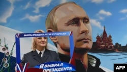 Жінка перед муралом із зображенням Владіміра Путіна під час виборів на дільниці в Донецьку, 15 березня, 2024. (Фото STRINGER / AFP)