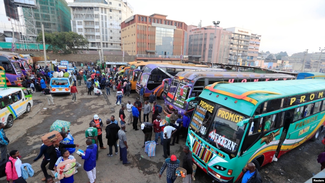 Passengers gather to board disinfected public transport buses as residents leave for the villages amid concerns over the spread of COVID-19 in downtown Nairobi, Kenya, March 25, 2020. 