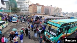 Passengers gather to board disinfected public transport buses as residents leave for the villages amid concerns over the spread of COVID-19 in downtown Nairobi, Kenya, March 25, 2020. 