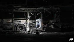 An Israeli police officer inspects the scene of one of a series of bus explosions in what authorities said appeared to be a militant attack in Bat Yam, central Israel, Feb. 20, 2025.