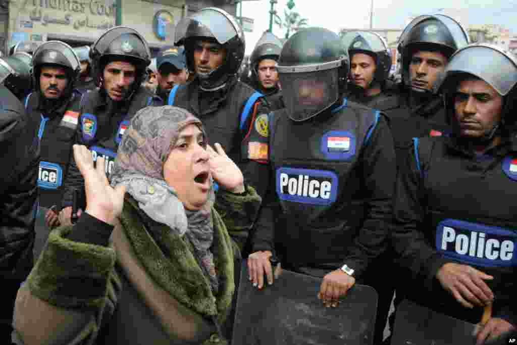 A woman reacts as she stands before riot policemen separating opponents of Egyptian President Mohamed Morsi and Islamist supporters of the president in Alexandria, Egypt, December 21, 2012.