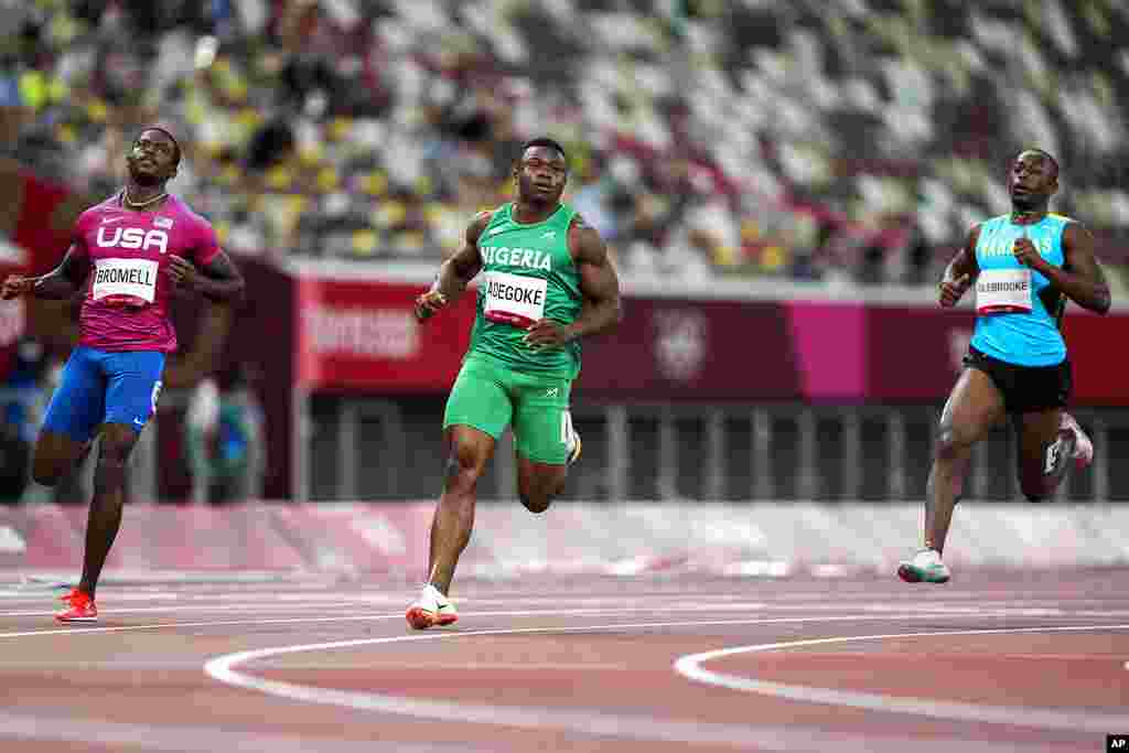 Enoch Adegoke, of Nigeria, center, wins a heat in the men&#39;s 100-meter run at the 2020 Summer Olympics, Saturday, July 31, 2021, in Tokyo. (AP Photo/Martin Meissner)