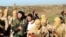 An image from Raqqa Media Center of the Islamic State group, which has been authenticated based on its contents and other AP reporting, shows Islamic State fighters with what is believed to be a captured pilot, center, in a white shirt, in Raqqa, Syria, Dec. 24, 2014.