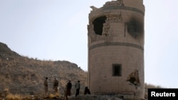 Houthi fighters stand near a damaged guard post at a Presidential Guards barracks they took over on a mountain overlooking the Presidential Palace in Sanaa, Jan. 20, 2015.