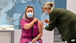 Health care worker Sanna Elkadiri, left, the first Dutch recipient of a COVID vaccine, gets her shot of the Pfizer-BioNTech coronavirus vaccine at a vaccination center in Veghel, Netherlands, Jan. 6, 2021. 