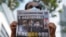 Seorang pendukung pro-demokrasi menunjukkan koran Apple Daily saat persidangan dua eksekutif koran pro-demokrasi atas tuduhan pelanggaran Undang-Undang Keamanan Nasional, di Hong Kong, China, 19 Juni 2021. (Foto: Lam Yik/Reuters)