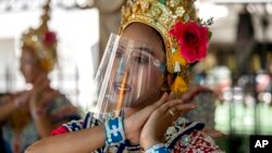 A Thai classical dancer wearing face shield to help curb the spread of the coronavirus performs at the Erawan Shrine in Bangkok, Thailand.