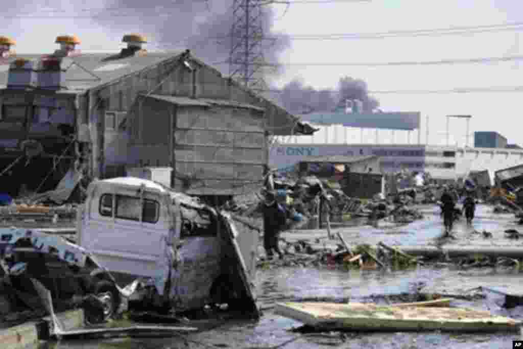 Local residents walk though a devastated street in Tagajo, Miyagi prefecture on March 13, 2011 following a massive earthquake and tsunami on March 11.