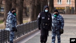 FILE - Police officers wearing face masks patrol at Patriarch Ponds in Moscow, Russia, April 22, 2020.