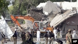 Pakistani soldiers, police officers check a police building after it was attacked by a suicide bomber in an explosives-laden pickup truck in Peshawar, Pakistan, May 25, 2011