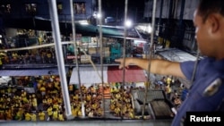 Seorang penjaga menunjuk narapidana yang berkumpul di lapangan basket di Penjara Kota Quezon di Manila, Filipina, 18 Oktober 2016. (Foto: Reuters)