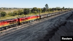 FILE:: A Transnet Freight Rail train is seen next to tons of coal mined from the nearby Khanye Colliery mine, at the Bronkhorstspruit station, in Bronkhorstspruit, around 90 kilometres north-east of Johannesburg, South Africa. Taken Apr 26, 2022.