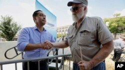 Mantan Menteri Perumahan dan Pembangunan Perkotaan Julian Castro berbicara dengan Mark Winslow dari Corydon, Iowa (kanan), saat mengunjungi pameran Iowa State Fair, 17 Agustus 2018, di Des Moines.
