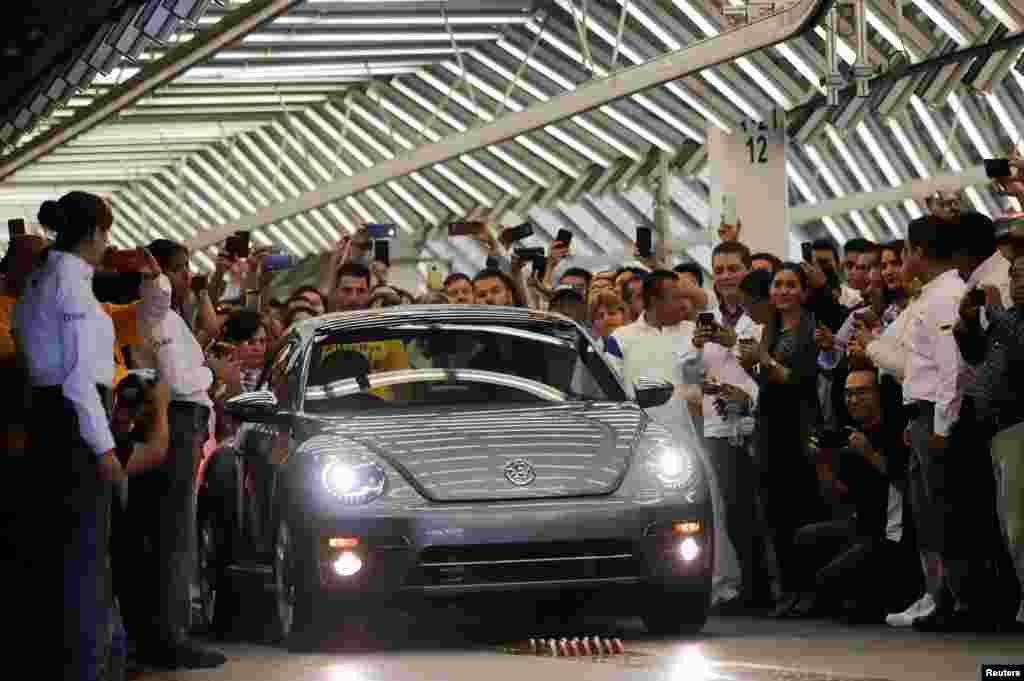 Employees take pictures of a Volkswagen Beetle car during a ceremony marking the end of production of VW Beetle cars, at the company's assembly plant in Puebla, Mexico, July 10, 2019. The last Beetle is not for sale, but destined instead for a museum.