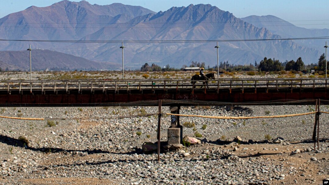 En esta foto del 23 de septiembre de 2019, un jinete cruza un puente sobre el lecho de un río que quedó seco por la peor sequía de Chile en más de medio siglo, en Putaendo. 