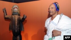 Le roi Behanzin du Bénin près d'une statue représentant son ancêtre du début du 19e siècle, le roi Behanzin, lors de sa visite au musée des arts primitifs du Quai Branly à Paris, le 7 avril 2010.