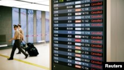 Pilots walk past an electronic board that shows canceled domestic flights because of Typhoon Soulik at Gimpo airport in Seoul, South Korea, Aug. 23, 2018.