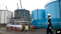 Seorang karyawan berjalan melewati tangki penyimpanan air yang terkontaminasi di pembangkit listrik tenaga nuklir Fukushima Dai-ichi yang lumpuh akibat tsunami di Jepang, 23 Februari 2017. (Foto: Tomohiro Ohsumi via AP)