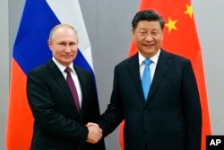 Presiden Rusia Vladimir Putin, kiri, dan Presiden China Xi Jinping berjabat tangan sebelum melakukan pembicaraan di sela-sela KTT BRICS edisi ke-11, di Brasilia, Brazil pada 12 November 2019. (Foto: via AP)