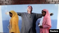 Employees of Grameen Bank walk in front of a portrait of Nobel laurate Muhammad Yunus in Dhaka March 8, 2011. (file)