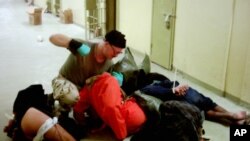 Sawirkan oo ay heshay AP, ayaa muujinaya askari lagu magacaabo Cpl. Charles A. Graner Jr. oo feeraya qaar ka mid ah maxaabiista oo dhulka jiifa ayagoo garbo duuban sanadkii 2003, xabsiga Abu Ghraib ee Baghdad, Iraq.